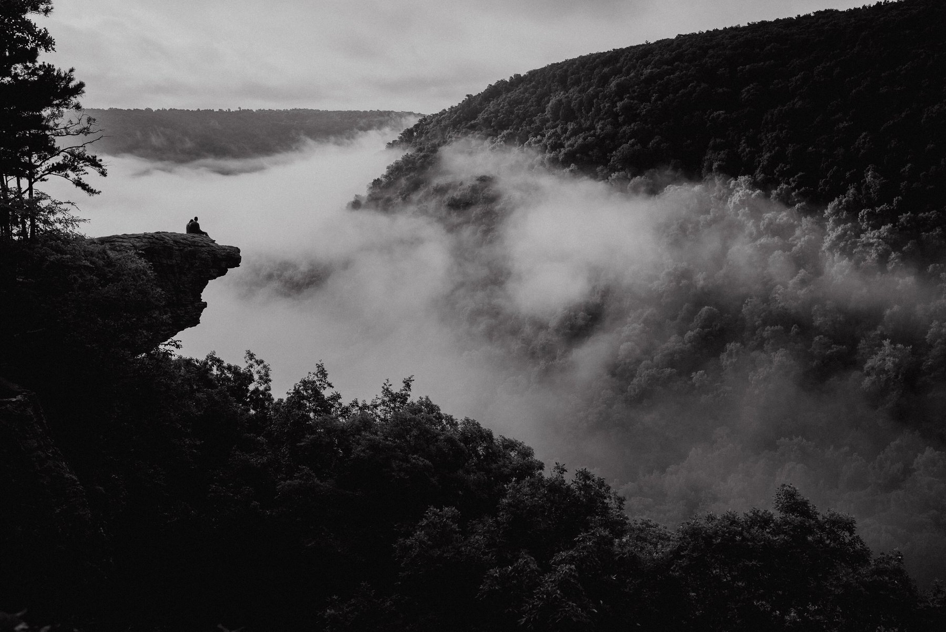 Sunrise engagement portrait at Hawksbill Crag in Arkansas with warm dawn light, cliffside views, and a dark dreamy cinematic film-look