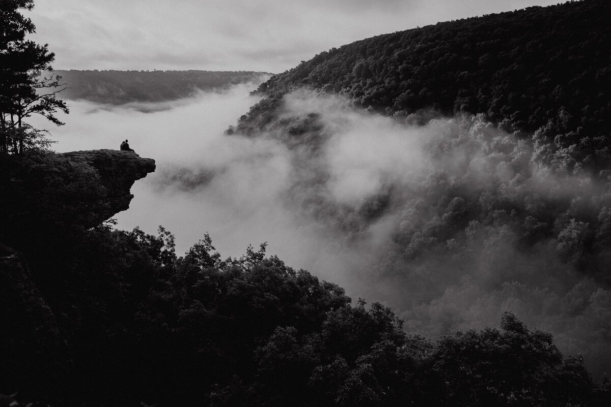 Sunrise engagement portrait at Hawksbill Crag in Arkansas with warm dawn light, cliffside views, and a dark dreamy cinematic film-look